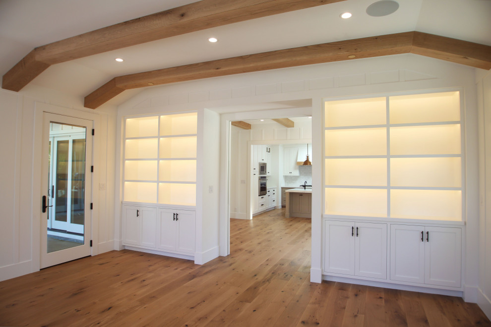 Large farmhouse enclosed games room in San Francisco with white walls, light hardwood flooring, a wall mounted tv and brown floors.