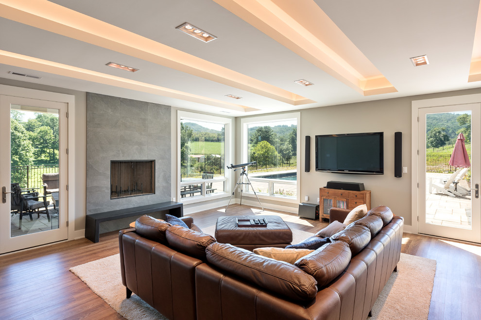 Photo of a large contemporary open plan games room in Other with beige walls, dark hardwood flooring, a standard fireplace, a tiled fireplace surround, a wall mounted tv and brown floors.