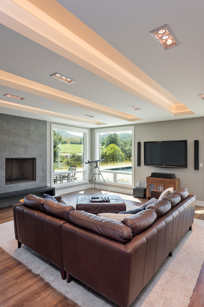 This is an example of a large contemporary open plan games room in Other with beige walls, dark hardwood flooring, a standard fireplace, a tiled fireplace surround, a wall mounted tv and brown floors.