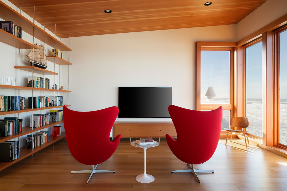 Cette image montre une salle de séjour design de taille moyenne avec un mur blanc, un téléviseur fixé au mur, une bibliothèque ou un coin lecture, un sol en bois brun et une cheminée ribbon.