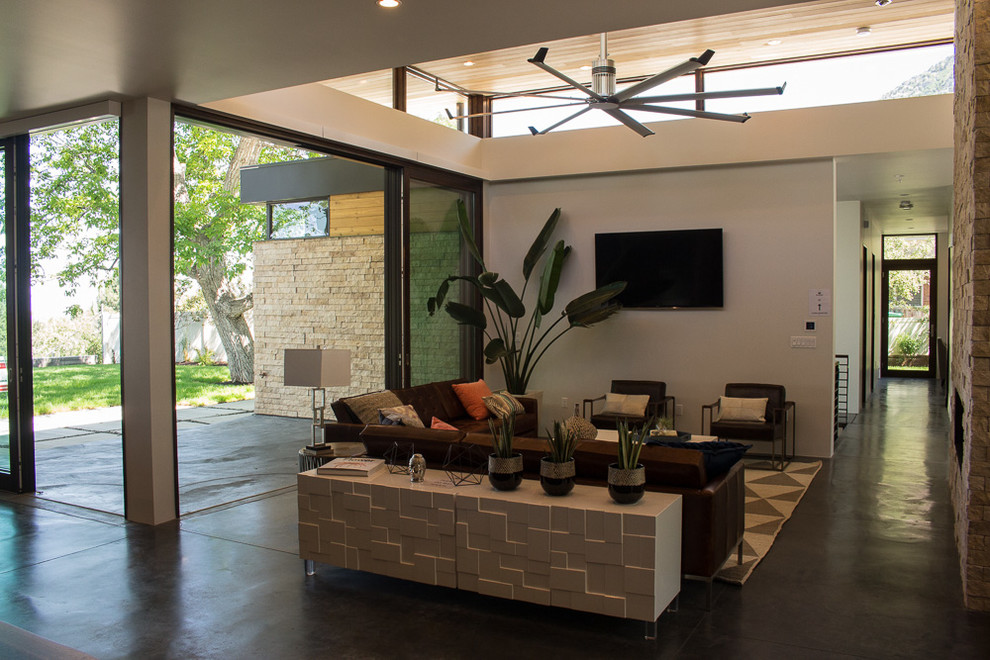 Inspiration for a mid-sized modern open concept concrete floor family room remodel in Salt Lake City with white walls, a standard fireplace, a stone fireplace and a wall-mounted tv