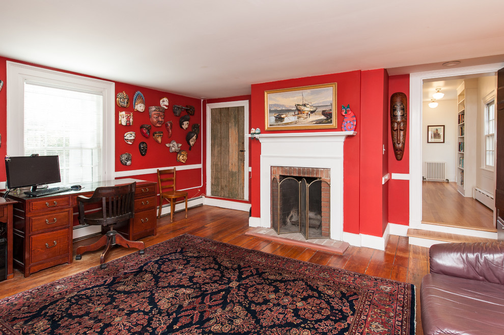 Inspiration pour une salle de séjour craftsman de taille moyenne et fermée avec une bibliothèque ou un coin lecture, un mur rouge, un sol en bois brun, une cheminée standard et un manteau de cheminée en bois.