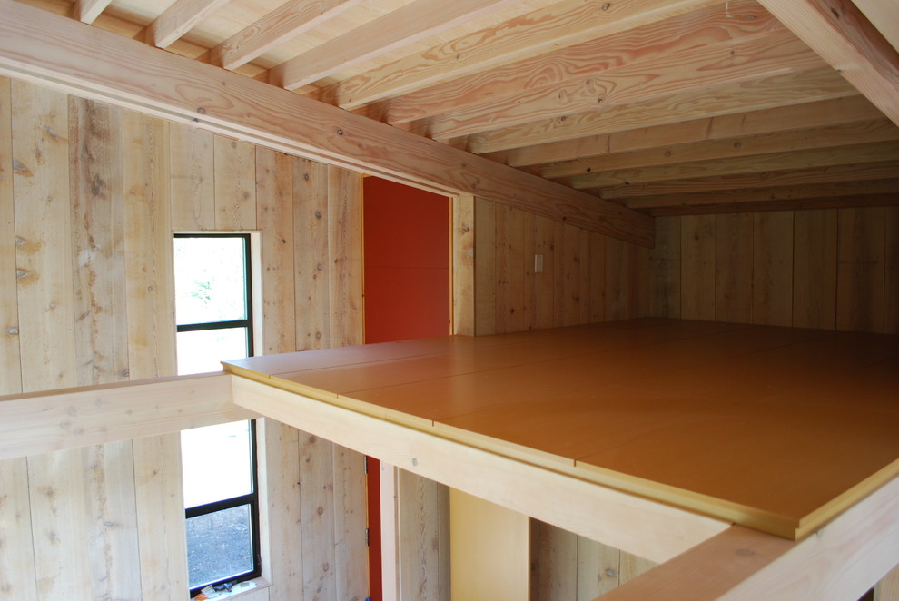 Imagen de sala de estar tipo loft contemporánea pequeña sin chimenea y televisor con paredes marrones y suelo de madera en tonos medios