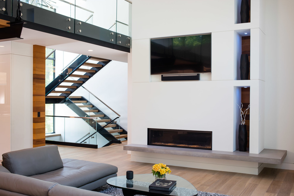 Ejemplo de sala de estar abierta contemporánea grande con paredes blancas, suelo de madera clara, chimenea lineal, pared multimedia y suelo marrón