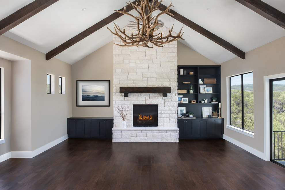 This is an example of an expansive traditional open plan games room in Austin with a game room, beige walls, dark hardwood flooring, a standard fireplace, a stone fireplace surround, a built-in media unit, brown floors and a vaulted ceiling.