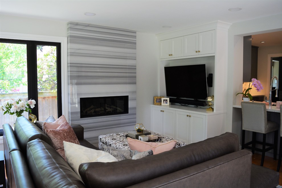Medium sized contemporary open plan games room in Toronto with grey walls, light hardwood flooring, a standard fireplace, a stone fireplace surround and a built-in media unit.