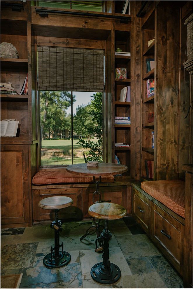 Idee per un grande soggiorno rustico chiuso con libreria, pareti marroni, pavimento in ardesia, camino classico, cornice del camino piastrellata e TV a parete