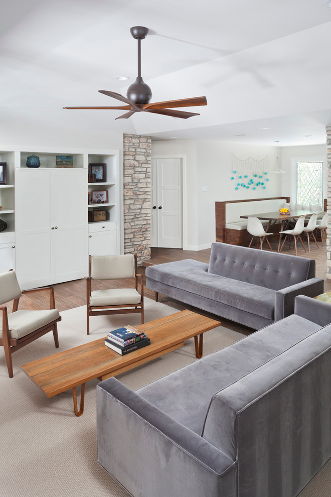Diseño de sala de estar abierta retro con paredes grises, suelo de baldosas de porcelana y televisor retractable