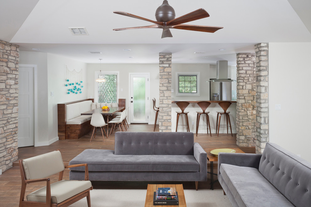 Offenes Retro Wohnzimmer mit grauer Wandfarbe, Porzellan-Bodenfliesen und verstecktem TV in Austin