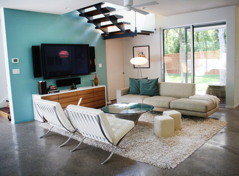 Family room - contemporary concrete floor family room idea in Austin with no fireplace, a wall-mounted tv and multicolored walls