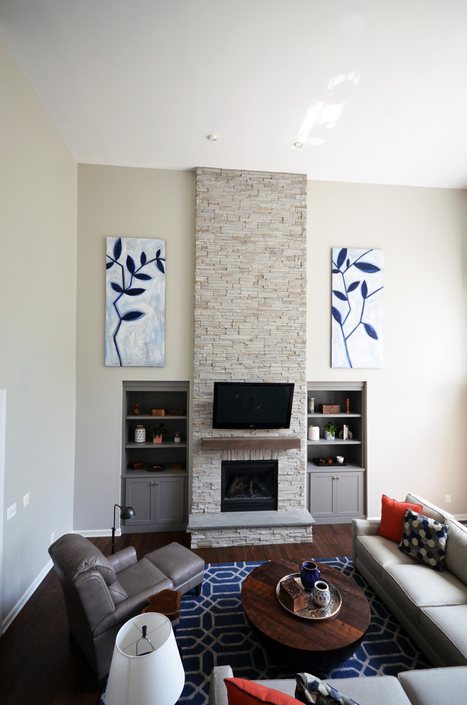 Exempel på ett stort modernt allrum med öppen planlösning, med grå väggar, mörkt trägolv, en standard öppen spis, en spiselkrans i sten, en väggmonterad TV och brunt golv