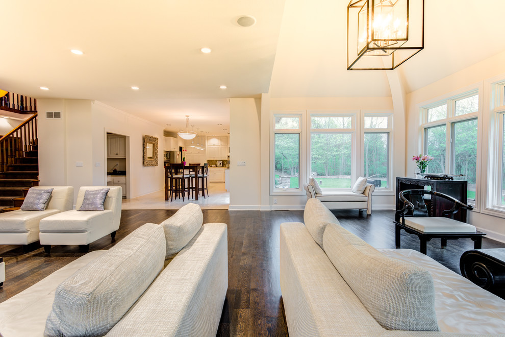 Example of a large trendy open concept dark wood floor and brown floor family room design in Milwaukee with white walls, a standard fireplace, a plaster fireplace and a wall-mounted tv