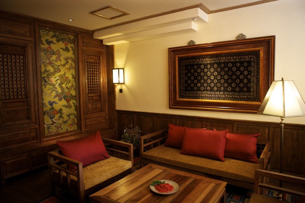 На фото: гостиная комната в восточном стиле с светлым паркетным полом, стандартным камином, фасадом камина из плитки и коричневым полом