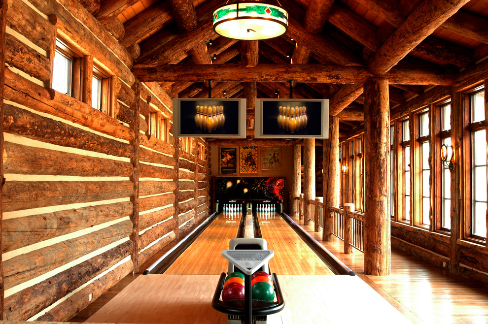 Cette image montre une salle de séjour chalet avec salle de jeu, un mur marron et un sol en bois brun.