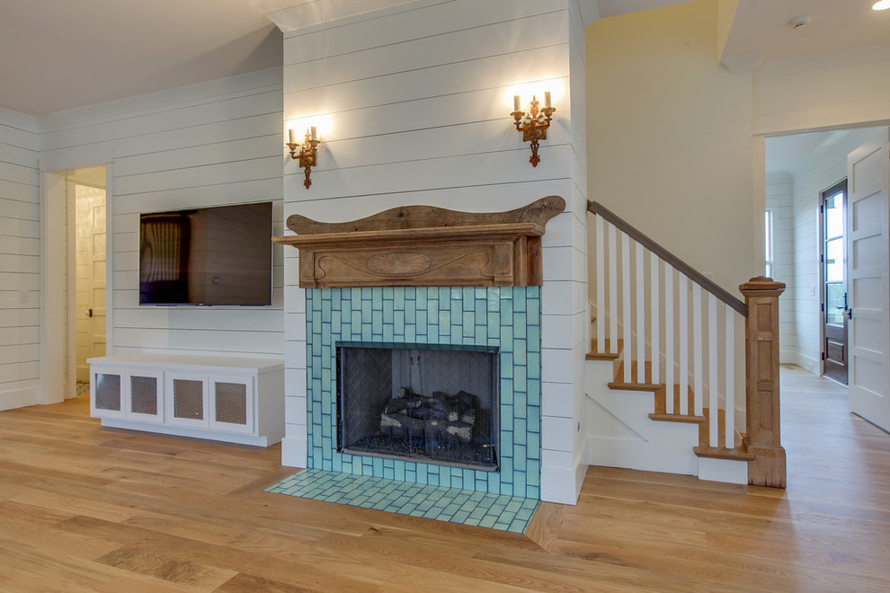 This is an example of a medium sized rural open plan games room in Nashville with white walls, light hardwood flooring, a standard fireplace, a tiled fireplace surround and a wall mounted tv.