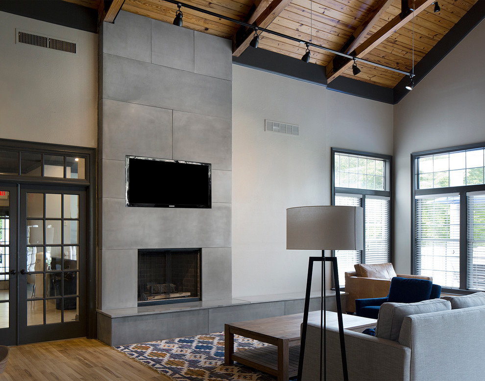 Modelo de sala de estar cerrada minimalista de tamaño medio con paredes blancas, suelo de madera clara, todas las chimeneas, marco de chimenea de hormigón y televisor colgado en la pared