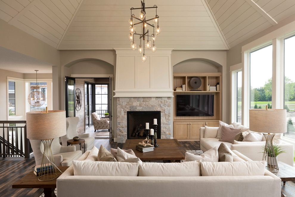 Inspiration pour un salon traditionnel ouvert avec un mur gris, une cheminée standard, un manteau de cheminée en pierre, un téléviseur encastré et un sol marron.