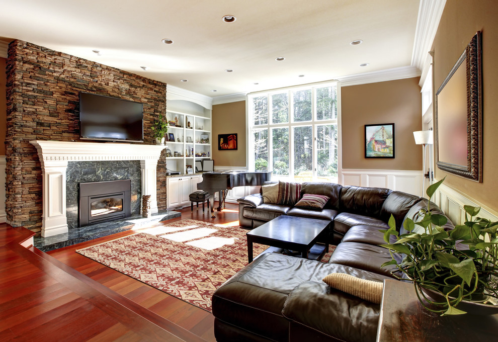 На фото: изолированная гостиная комната среднего размера в стиле кантри с коричневыми стенами, темным паркетным полом, стандартным камином, фасадом камина из камня, телевизором на стене и красным полом