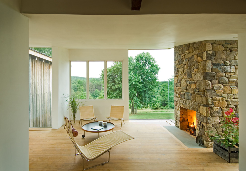 Immagine di un soggiorno minimal con pareti beige, pavimento in legno massello medio, camino classico e cornice del camino in pietra