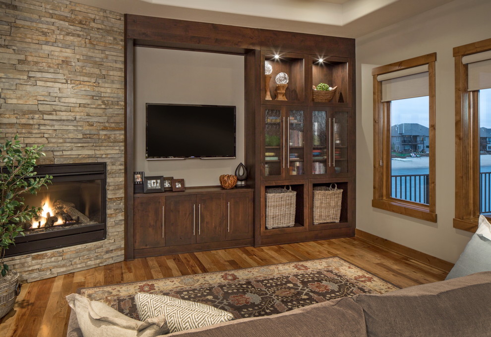 Idee per un soggiorno tradizionale con pareti beige, pavimento in legno massello medio, camino ad angolo, cornice del camino in pietra e TV a parete