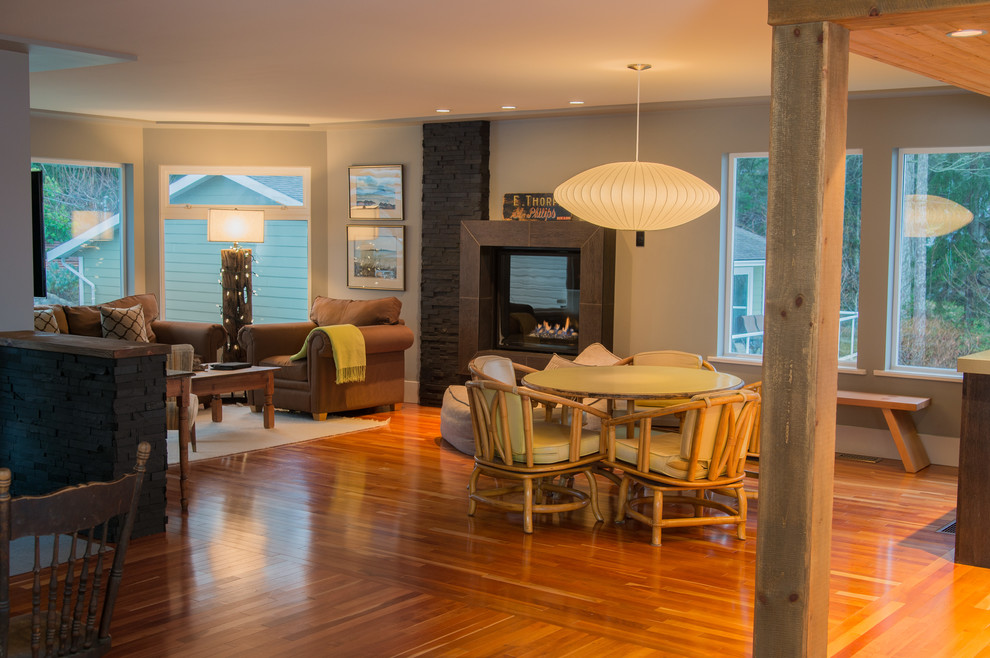 Diseño de sala de estar abierta contemporánea con paredes grises, suelo de madera en tonos medios y todas las chimeneas