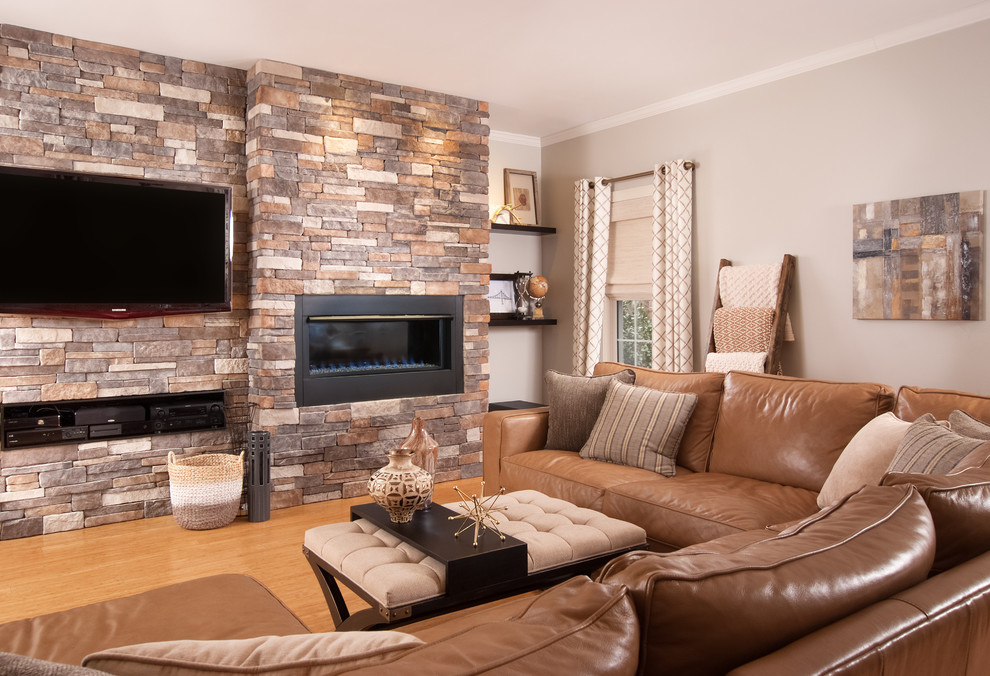 Foto de sala de estar cerrada contemporánea grande con paredes grises, suelo de madera clara, chimenea lineal, marco de chimenea de piedra, televisor colgado en la pared y suelo marrón