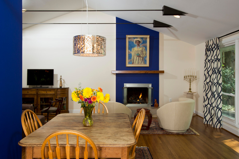 Cette image montre une salle à manger chalet de taille moyenne avec un mur bleu, parquet clair, une cheminée standard et un manteau de cheminée en métal.
