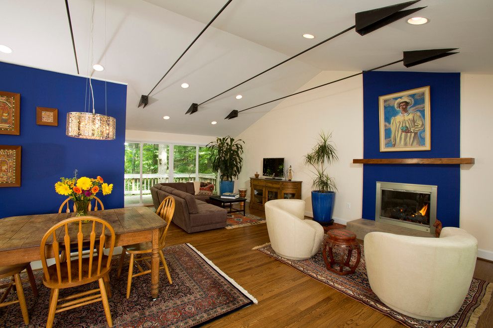 Cette photo montre une salle de séjour montagne de taille moyenne et ouverte avec un mur bleu, parquet clair, une cheminée standard et un manteau de cheminée en métal.