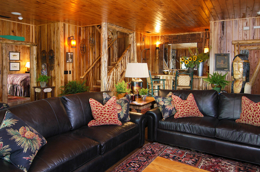 Cette image montre une grande salle de séjour chalet fermée avec un bar de salon, un mur marron, un sol en bois brun, une cheminée standard, un manteau de cheminée en pierre et aucun téléviseur.