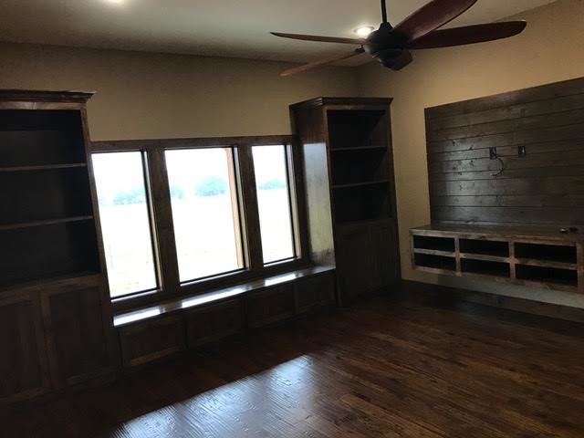 Imagen de sala de estar cerrada rural grande sin chimenea con paredes beige y suelo de madera oscura