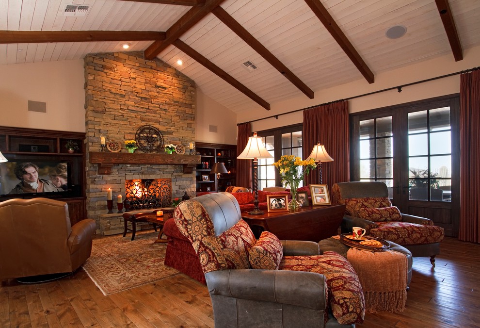 Rustic open plan games room in Phoenix with beige walls, medium hardwood flooring, a standard fireplace, a stone fireplace surround and a built-in media unit.