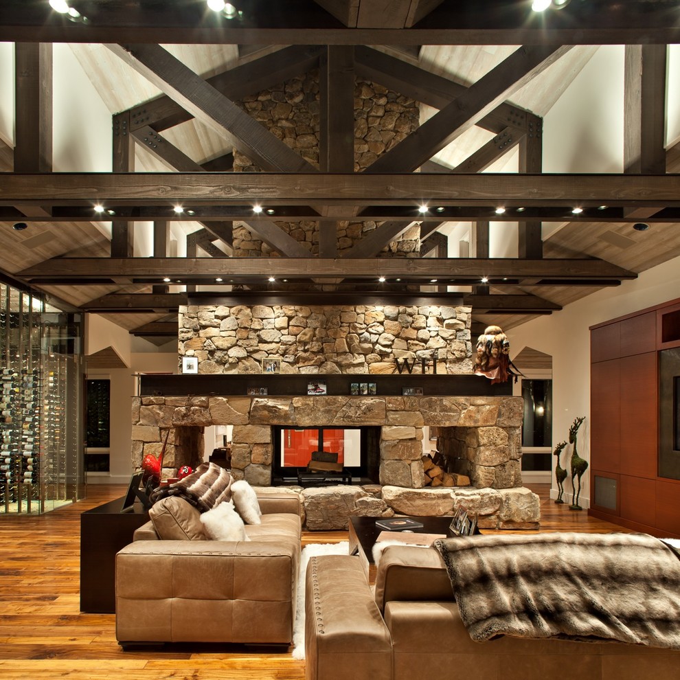 Стильный дизайн: гостиная комната в стиле рустика с двусторонним камином - последний тренд