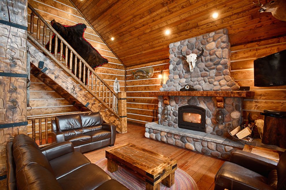 Design ideas for a large rustic enclosed games room in Other with brown walls, dark hardwood flooring, a wood burning stove, a stone fireplace surround, a wall mounted tv and brown floors.