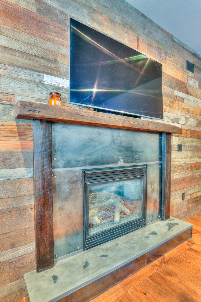 Foto på ett mellanstort rustikt avskilt allrum, med bruna väggar, en standard öppen spis, en spiselkrans i metall, mellanmörkt trägolv, en väggmonterad TV och brunt golv