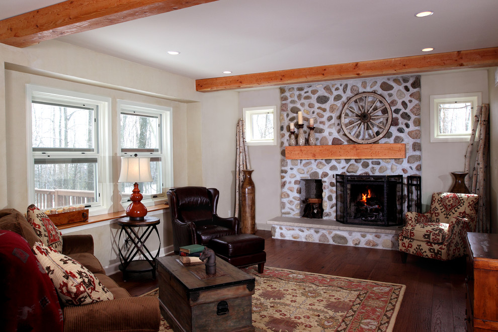 Rustikales Wohnzimmer mit beiger Wandfarbe, dunklem Holzboden, Kamin und Kaminumrandung aus Stein in Milwaukee