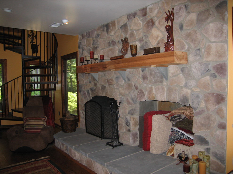 Exemple d'une salle de séjour montagne de taille moyenne et ouverte avec un mur jaune, un sol en bois brun, une cheminée standard et un manteau de cheminée en pierre.