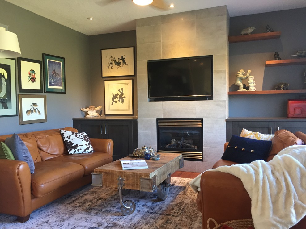 Photo of a medium sized contemporary open plan games room in Calgary with grey walls, medium hardwood flooring, a standard fireplace, a tiled fireplace surround and a built-in media unit.