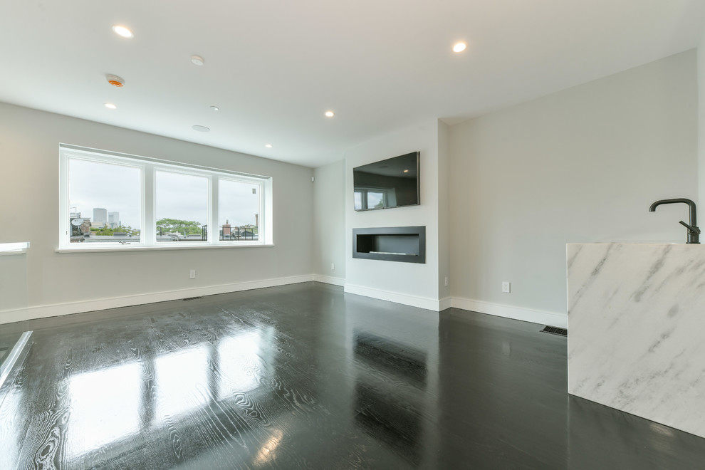 Mittelgroßes, Abgetrenntes Modernes Wohnzimmer mit Hausbar, grauer Wandfarbe, gebeiztem Holzboden, Gaskamin, verputzter Kaminumrandung, TV-Wand und schwarzem Boden in Boston