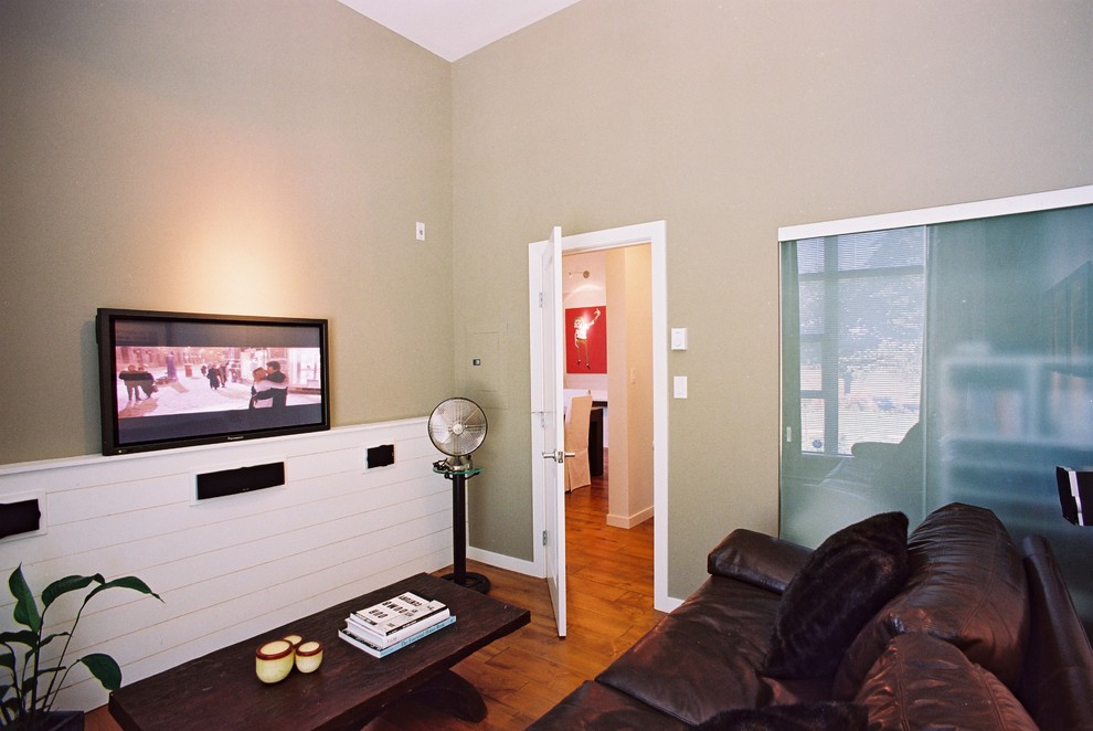 バンクーバーにある高級な中くらいなインダストリアルスタイルのおしゃれな独立型ファミリールーム (無垢フローリング、壁掛け型テレビ、ベージュの壁、暖炉なし、茶色い床) の写真