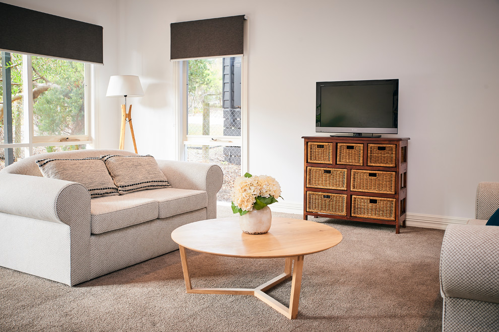 Imagen de sala de juegos en casa abierta costera de tamaño medio con paredes blancas, moqueta, televisor independiente y suelo marrón