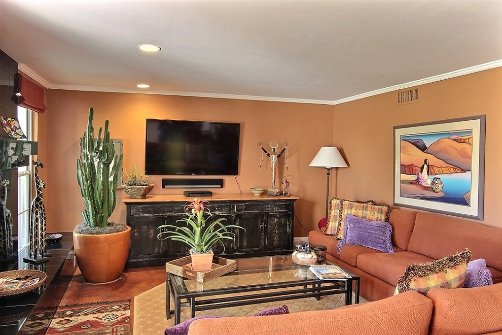 На фото: открытая гостиная комната среднего размера в стиле фьюжн с оранжевыми стенами, стандартным камином, фасадом камина из камня и телевизором на стене