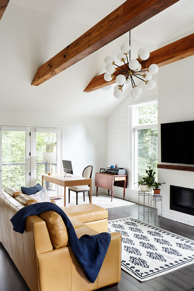 Imagen de sala de estar campestre con paredes blancas, suelo de madera oscura, todas las chimeneas, marco de chimenea de ladrillo, televisor colgado en la pared, suelo marrón y alfombra