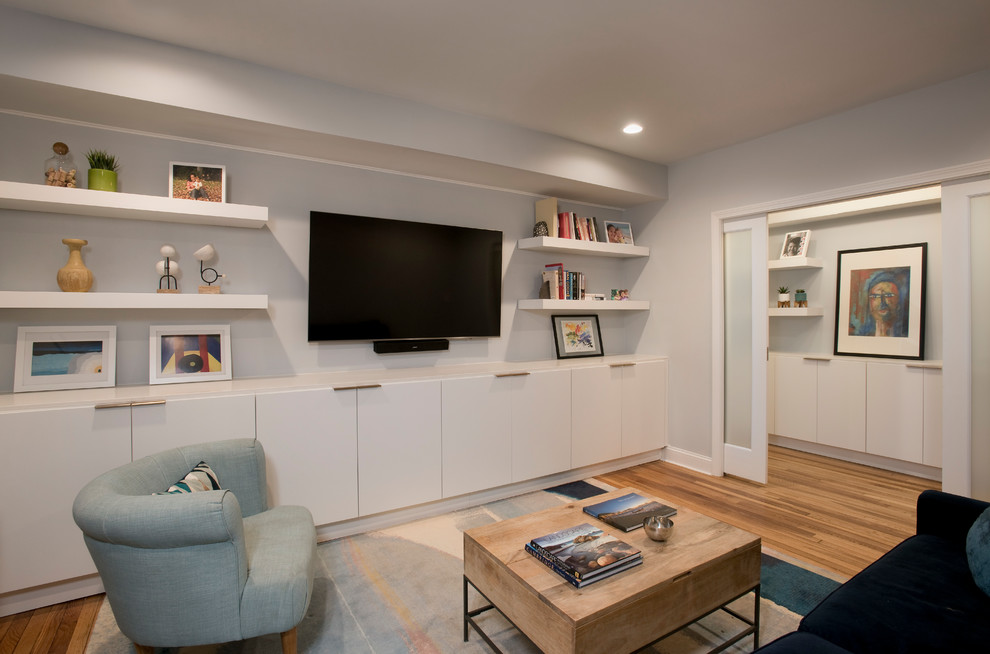 На фото: маленькая изолированная гостиная комната в стиле модернизм с серыми стенами, паркетным полом среднего тона и телевизором на стене для на участке и в саду с
