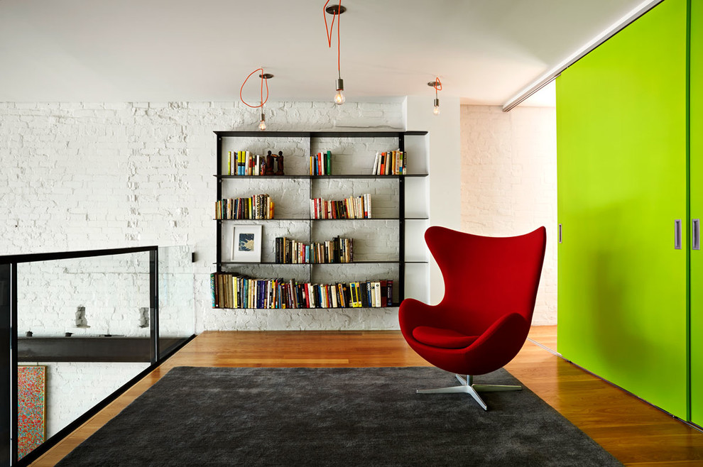 Example of a trendy loft-style medium tone wood floor family room library design in DC Metro with white walls and no tv
