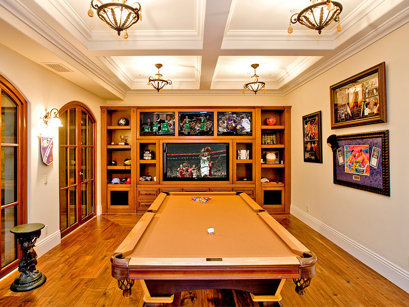 Modelo de sala de juegos en casa de estilo de casa de campo con paredes blancas, suelo de madera en tonos medios y pared multimedia