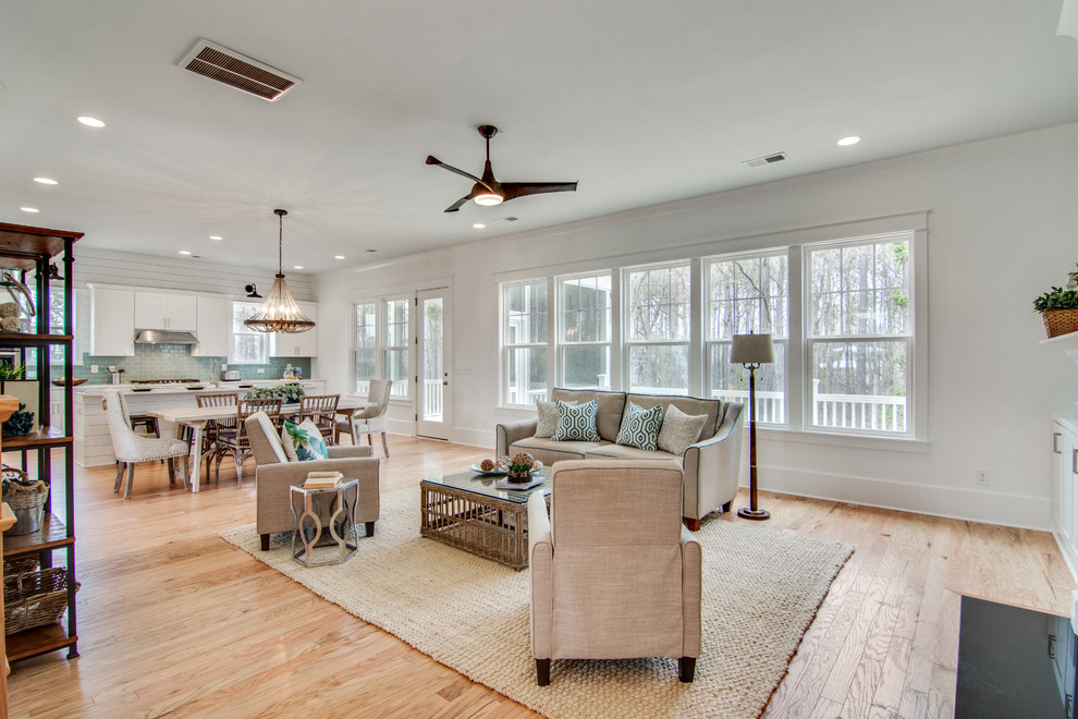 Foto de sala de estar abierta costera con suelo de madera clara