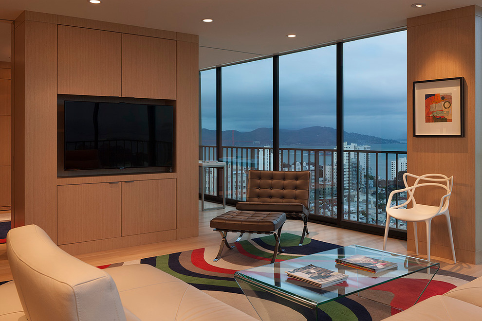 Imagen de sala de estar contemporánea sin chimenea con suelo de madera clara y pared multimedia