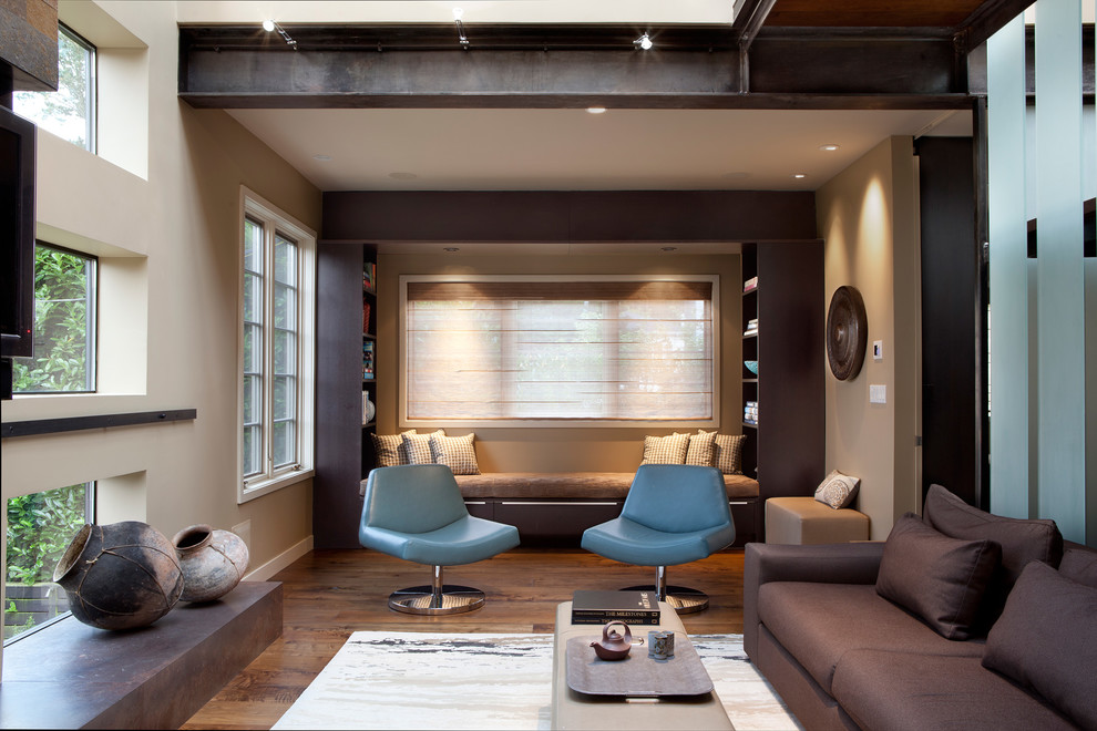 Imagen de sala de estar abierta actual grande con paredes beige, suelo de madera oscura y televisor colgado en la pared