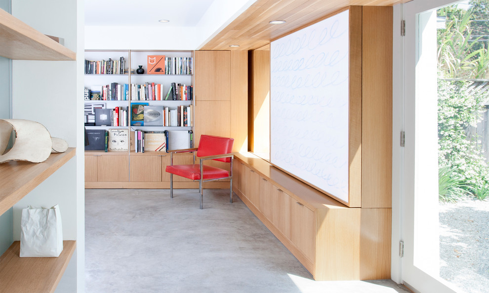 Foto di un soggiorno minimalista con libreria, pareti bianche e pavimento in cemento