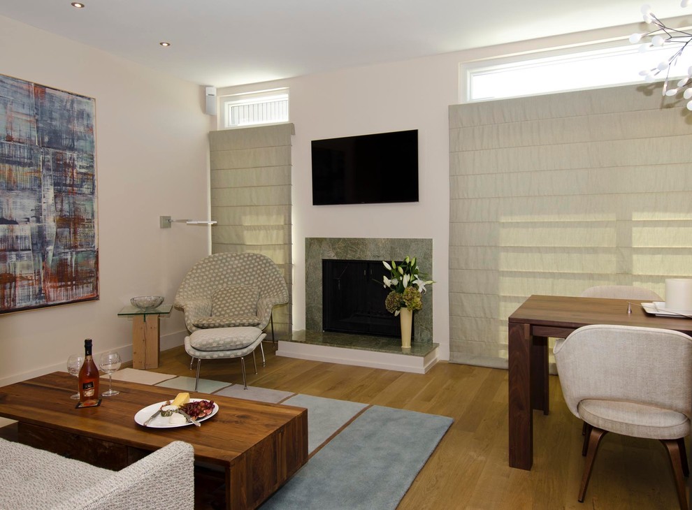 Foto di un soggiorno minimalista di medie dimensioni con pareti bianche, parquet chiaro, camino classico, cornice del camino in pietra e TV a parete